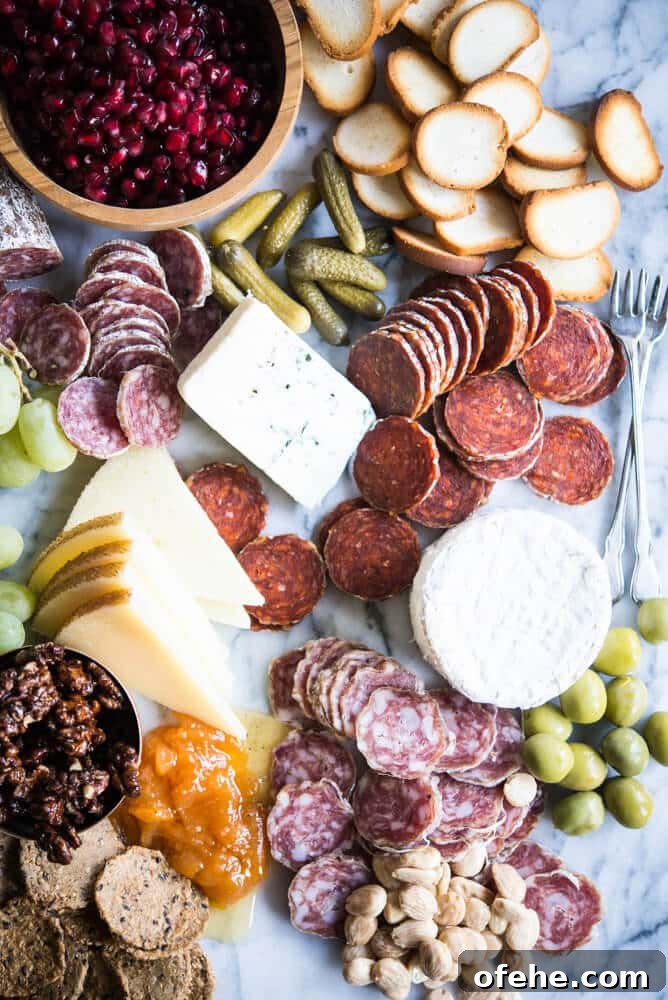 Build a Stunning Charcuterie Board: Expert Tips for Entertaining 4 Charcuterie board with meats, cheeses, honey, nuts, a wooden bowl of pomegranates, olives, grapes, pickles, crackers, on a marble board