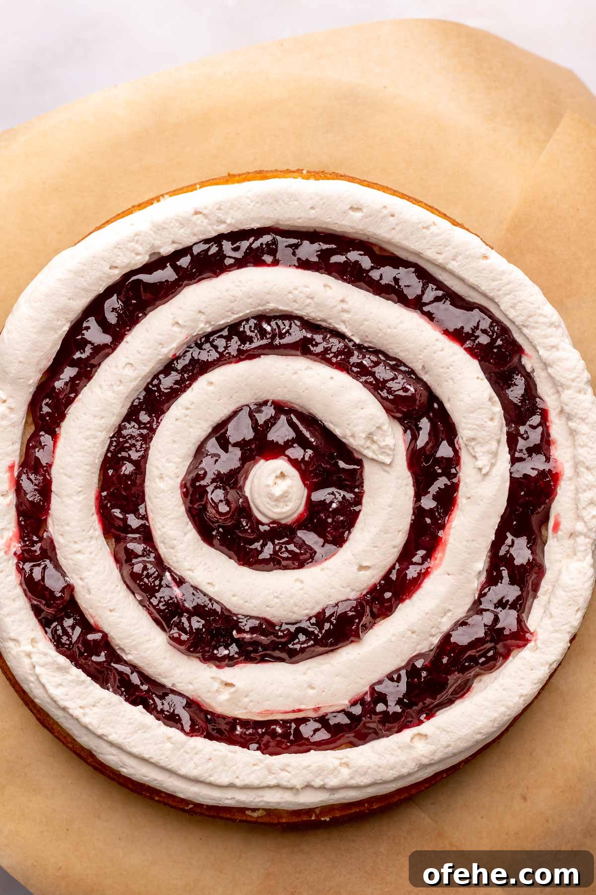 Raspberry Coconut Cake Recipe with Creamy Coconut Frosting 13 Raspberry jam piped inside the frosting in a bullseye pattern on a cake round.