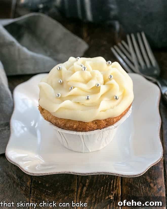 Vanilla Cupcakes with Cream Cheese Frosting are perfect for any occasion! They're sweet, tender and topped with mounds of rich, slightly tangy frosting. Vanilla cupcake on a square white plate.