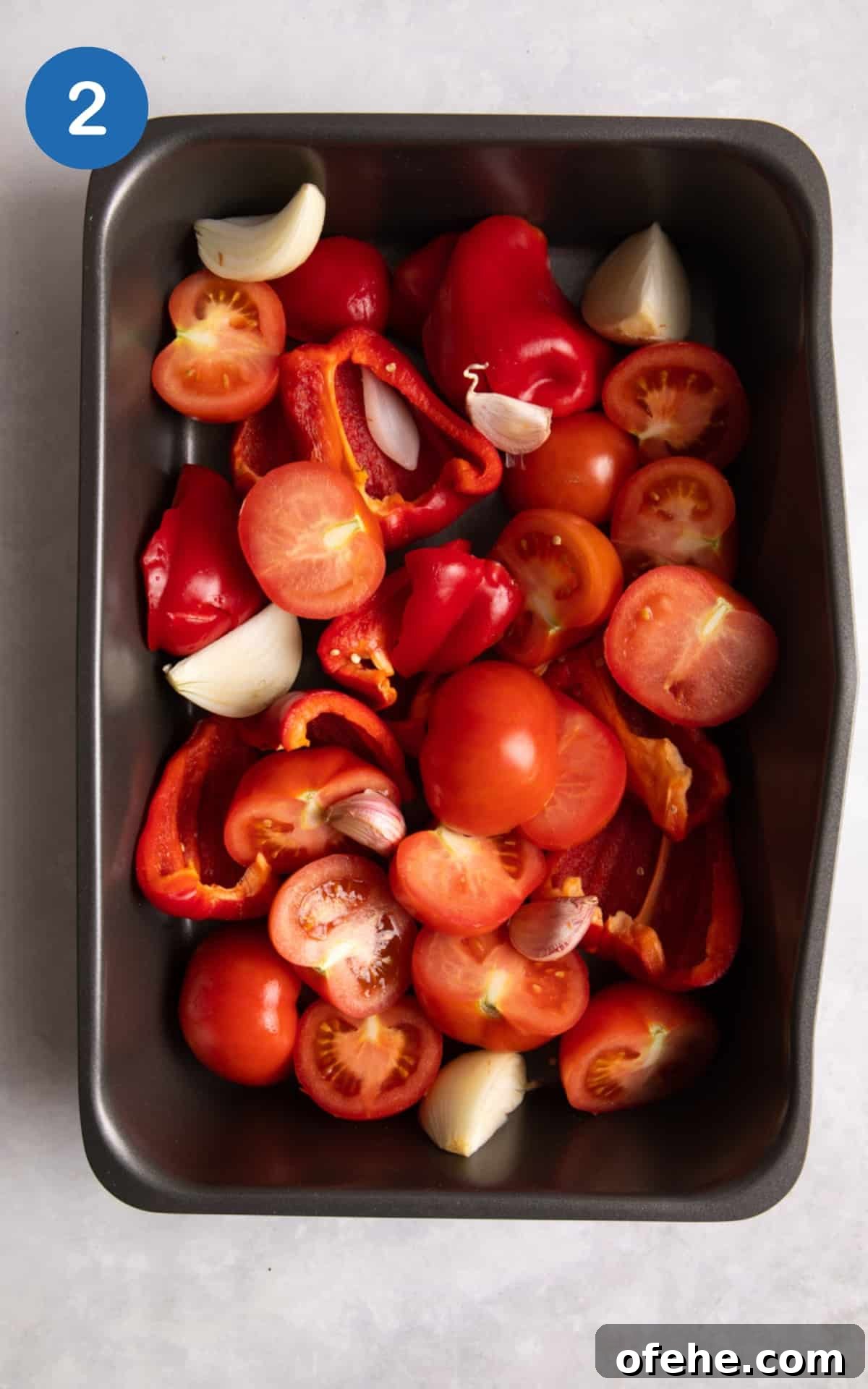 Roasted Red Pepper & Tomato Soup Recipe for Cozy Weeknights 5 tomatoes, pepper, onion and garlic all in a silver baking tray ready to bake.