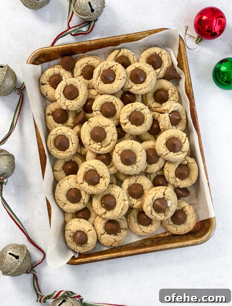 Classic Peanut Butter Blossom Cookies Recipe — Chewy & Chocolate-Topped 2 peanut butter blossom cookies stacked on top of each other with some bells and ornaments on the sides