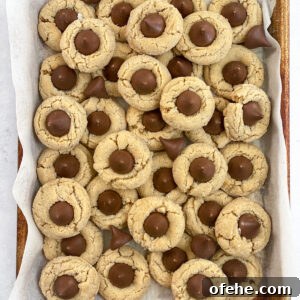 Classic Peanut Butter Blossom Cookies Recipe — Chewy & Chocolate-Topped 13 peanut butter blossom cookies all stacked on top of each other in the pan.