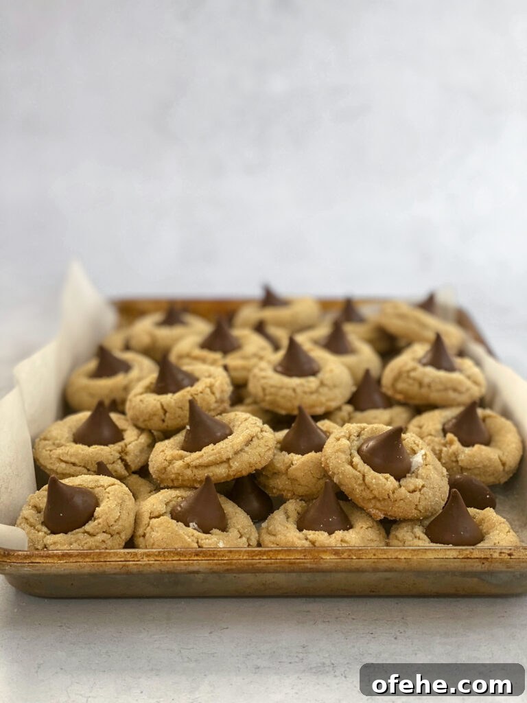 Classic Peanut Butter Blossom Cookies Recipe — Chewy & Chocolate-Topped 3 peanut butter blossom cookies filling a cookie sheet and over flowing