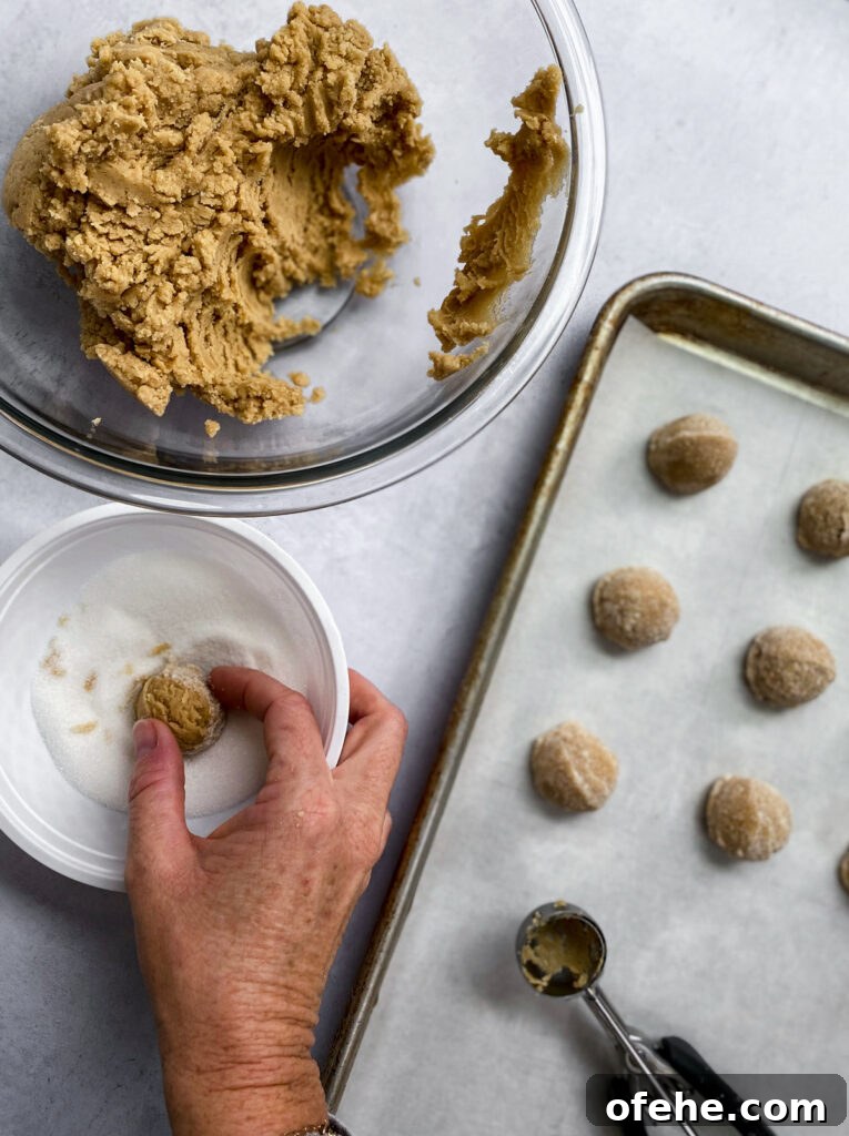 Classic Peanut Butter Blossom Cookies Recipe — Chewy & Chocolate-Topped 7 rolling cookies in sugar