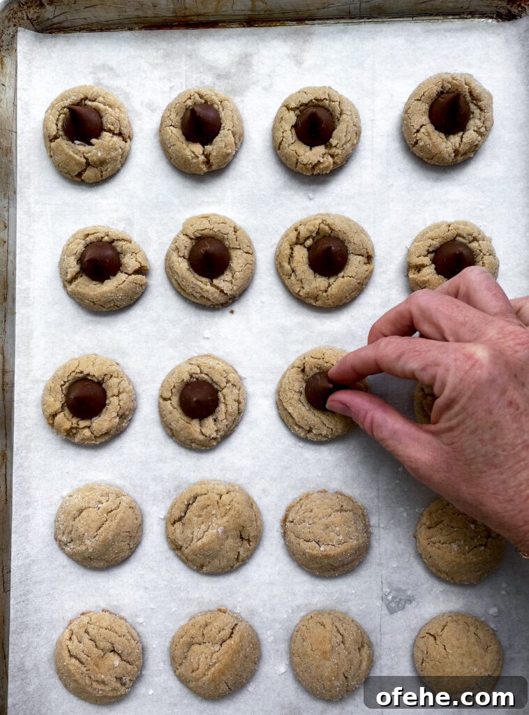 Classic Peanut Butter Blossom Cookies Recipe — Chewy & Chocolate-Topped 10 placing hershey kisses on top