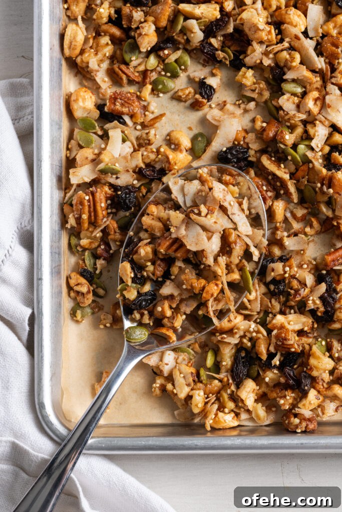 Grain-Free Homemade Granola Recipe with Crunchy Seeds 2 silver spoon on the bottom left corner of a parchment lined baking sheet scooping up some healthy grain free granola.