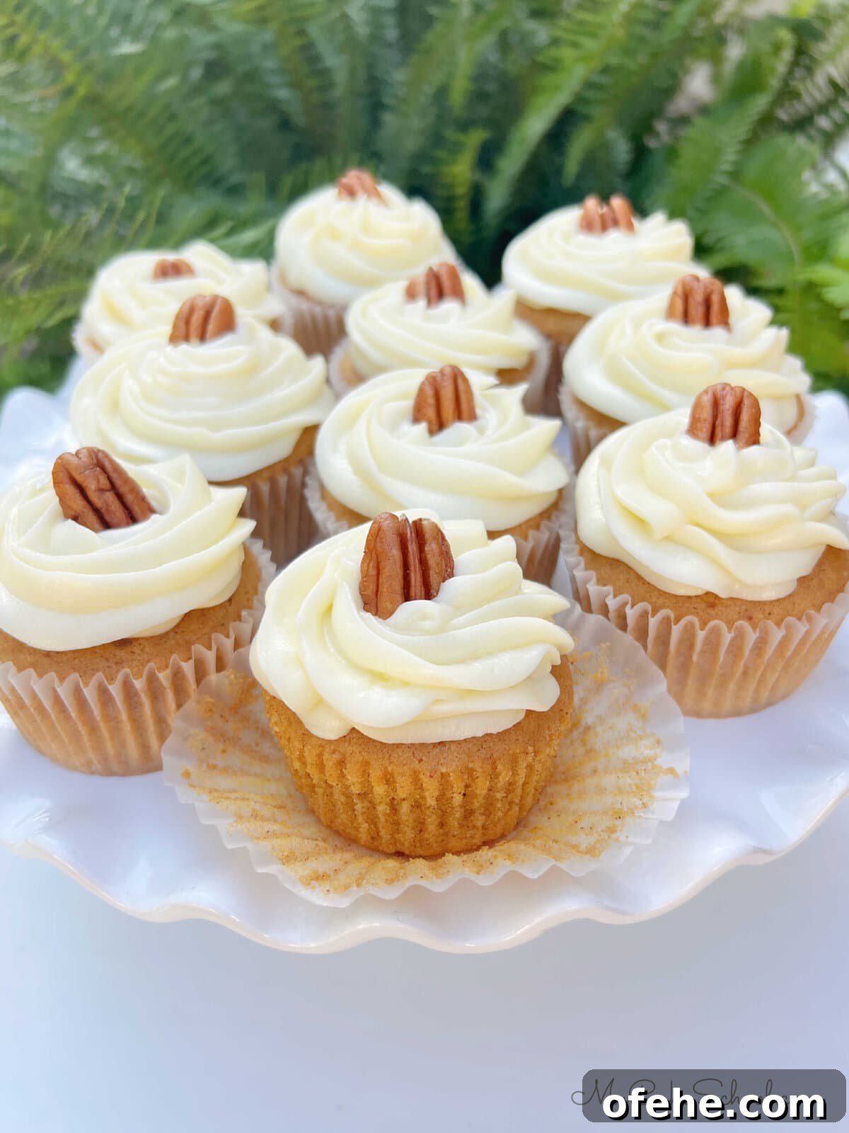 Moist Sweet Potato Cupcakes with Cinnamon Glaze 2 Homemade Sweet Potato Cupcakes, frosted with cream cheese frosting, on a cake pedestal.