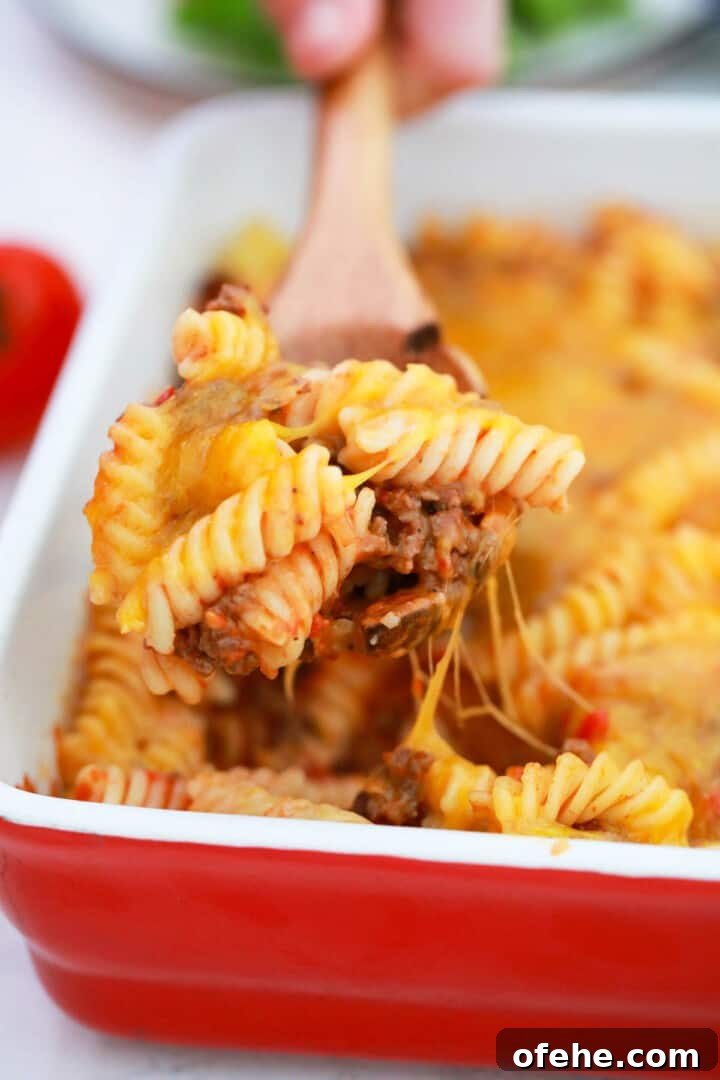 Cheeseburger Casserole Recipe: Simple Weeknight Comfort Bake 2 Cheeseburger Casserole in red casserole dish being scooped out