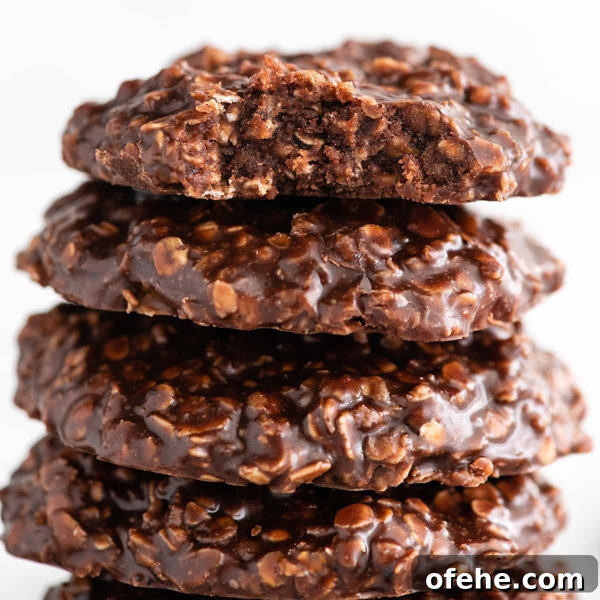 a close up photo of four no bake cookies, top one has a bite taken out of it so the moist frudgy textue is visible