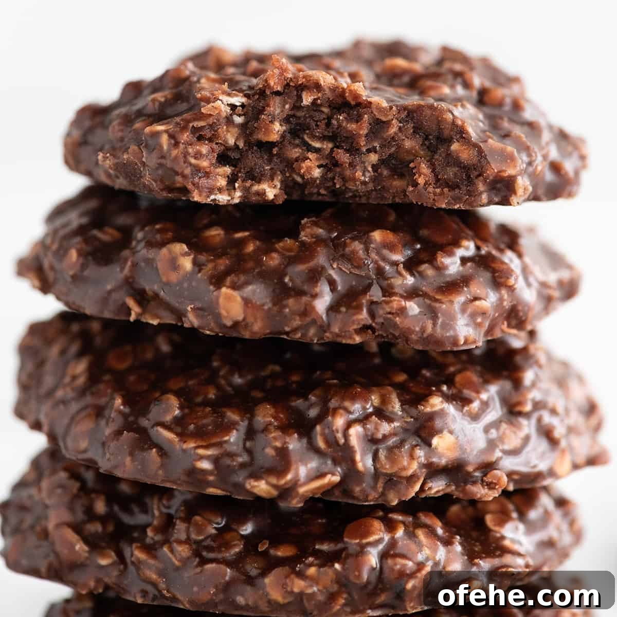 a close up photo of four no bake cookies, top one has a bite taken out of it so the moist frudgy textue is visible