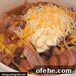 Leftover Pulled Pork Chili served with sour cream and cheese in a white bowl
