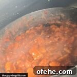 Smoked Loaded Baked Beans cooking in cast iron dutch oven in pellet grill