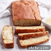A partially sliced loaf of crusty keto bread with one sliced and buttered.