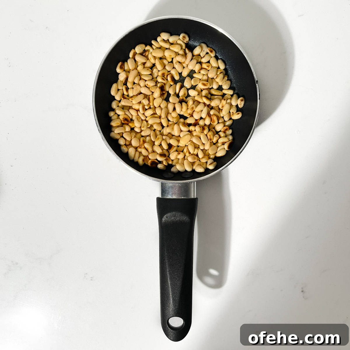 Fresh Arugula Pesto Recipe: Zesty Sauce for Pasta & Sandwiches 4 Toasting pine nuts in a small pan.