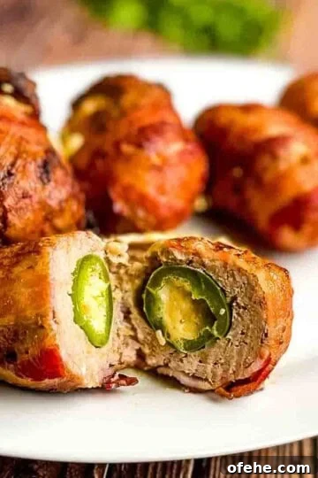 Air fryer armadillo eggs on a white serving platter, with one cut open in the middle.