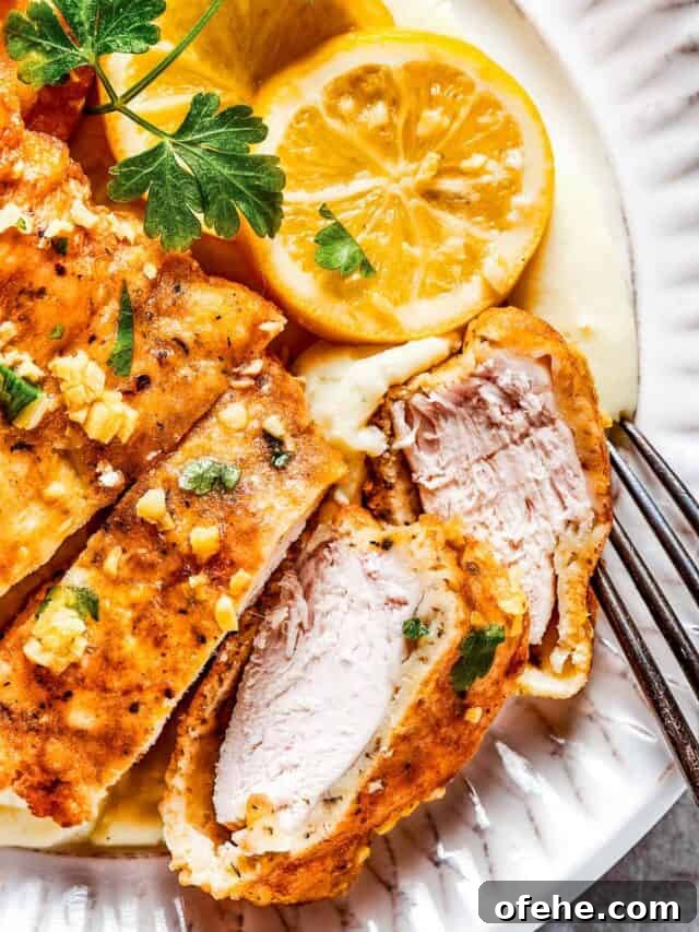 Plated lemon chicken. Sliced Breaded chicken with parsley and lemon slices placed next to it.