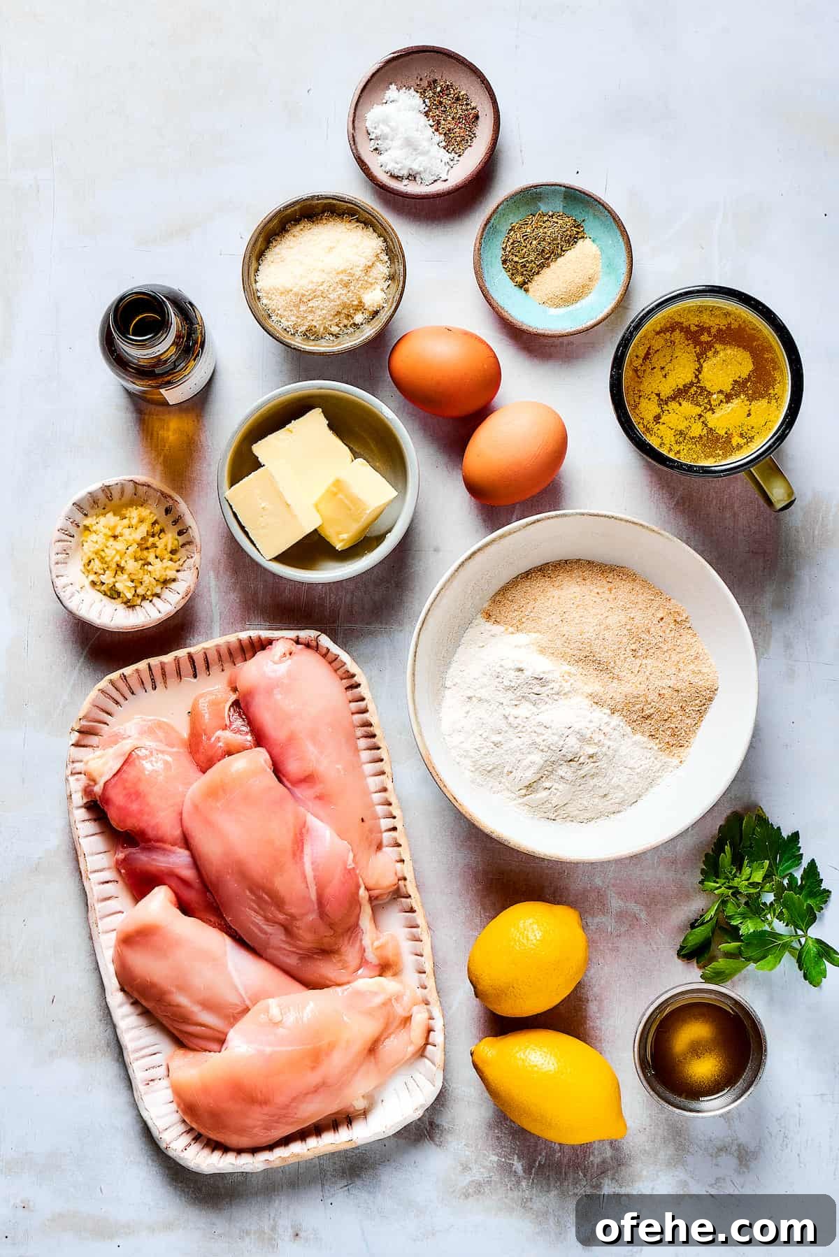 Wondering what to make for dinner? Try this easy Lemon Chicken Recipe! Crispy, parmesan-crusted chicken with real lemon butter sauce. Yum! From top: salt, pepper, garlic, Italian seasoning, broth, eggs, breadcrumbs, flour, parsley, olive oil, lemons, chicken breast, butter, garlic, parmesan, white wine.