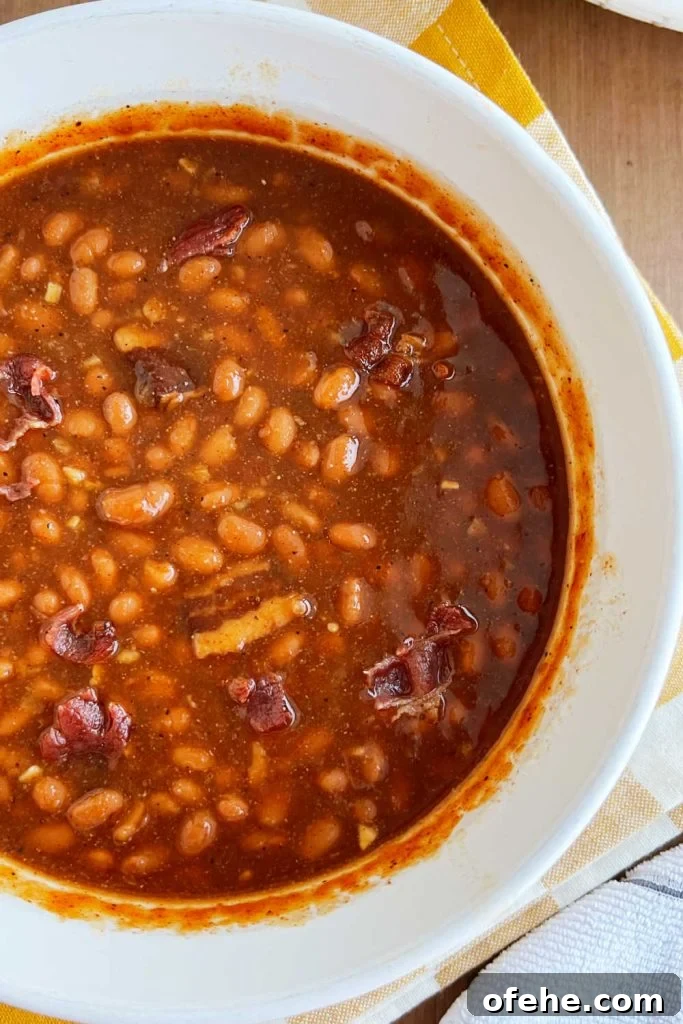 closeup of baked beans in casserole dish with bacon and brown sugar