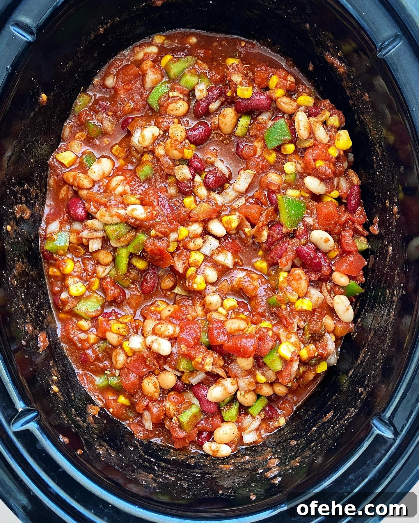 Hearty Crockpot Vegan Chili Recipe for Slow Cooker Success 4 overhead shot of uncooked ingredients for the best crockpot vegan chili in a black slow cooker