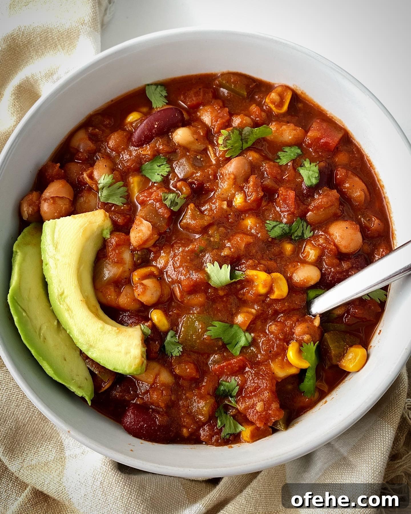 Hearty Crockpot Vegan Chili Recipe for Slow Cooker Success 6 overhead shot of cooked best crockpot vegan chili in a white bowl garnished with cilantro and sliced avocado
