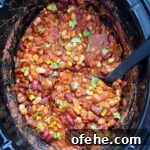 overhead shot of cooked the best crockpot vegan chili in a black slow cooker garnished with cilantro