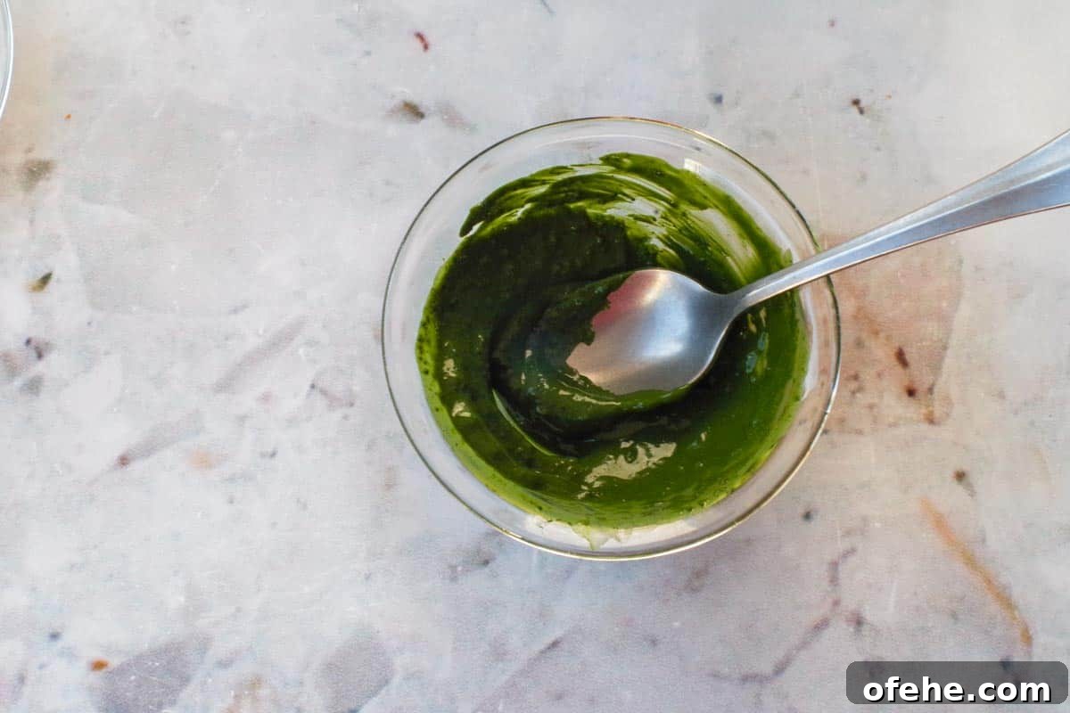 Colorful Earth Day Sheet-Pan Pancakes Recipe 9 Matcha mixed with a little water to make a paste in a small glass bowl, with a spoon.