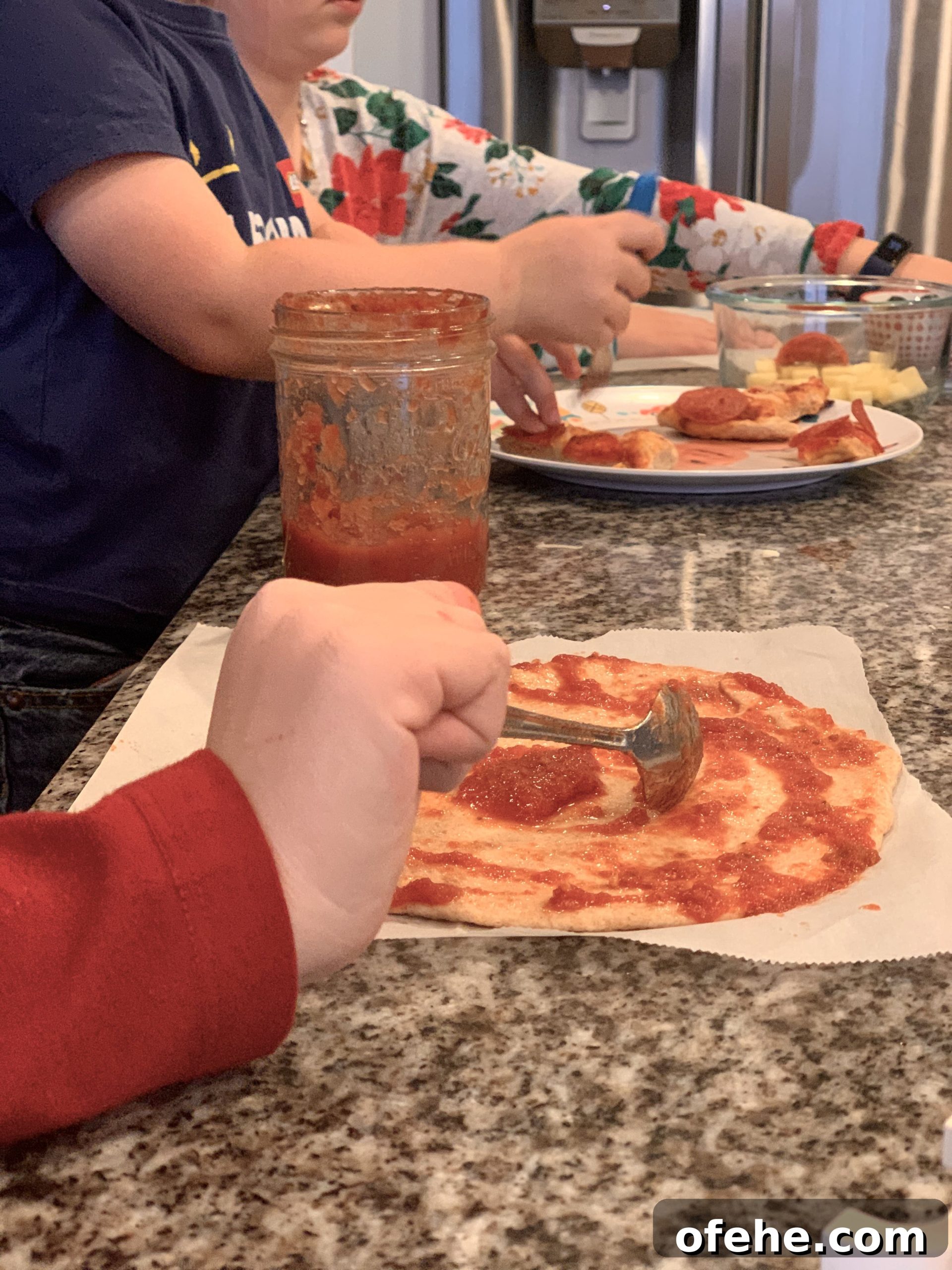 Kids saucing their own pizzas