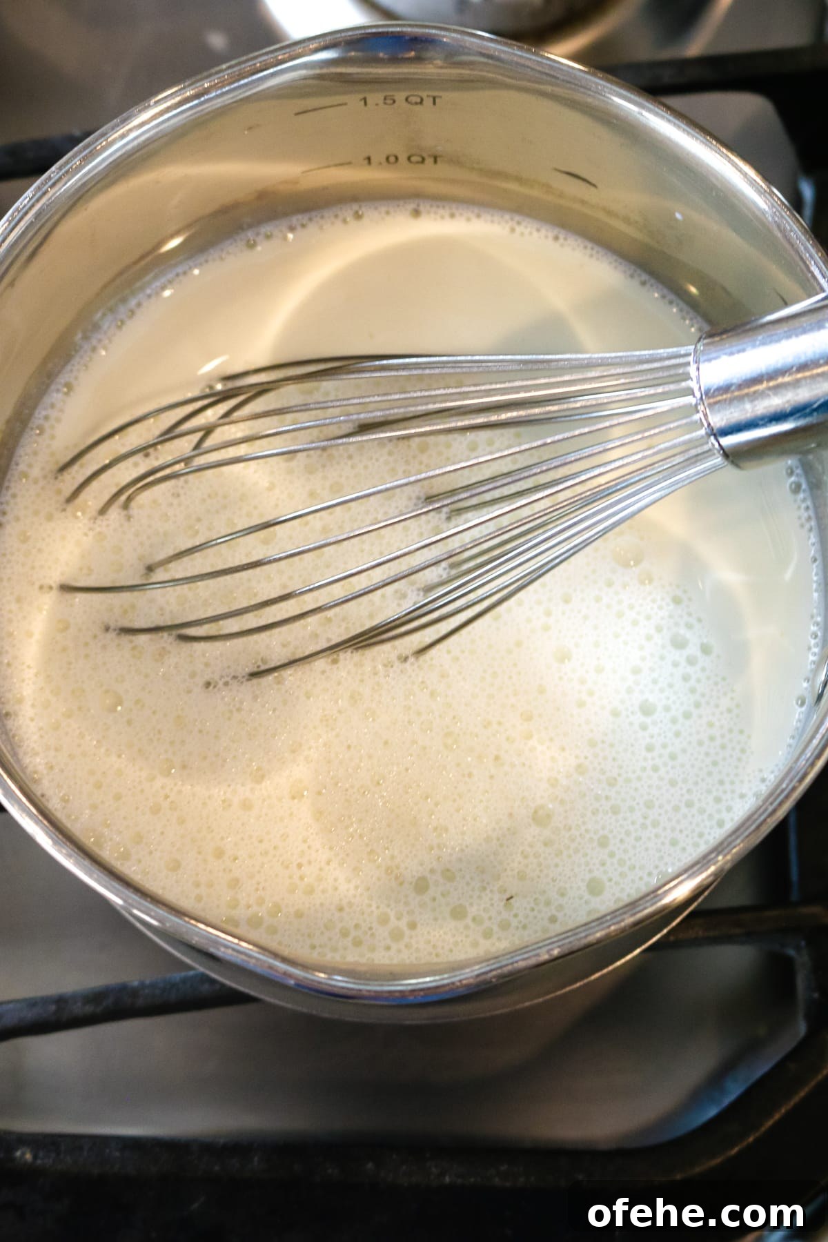 a whisk inside of a metal pan mixing milk.