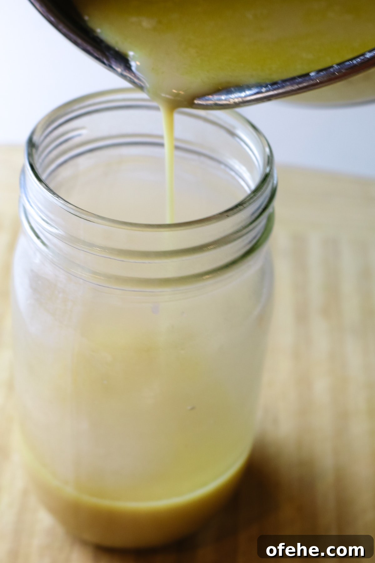 hot condensed milk being poured into mason jar.