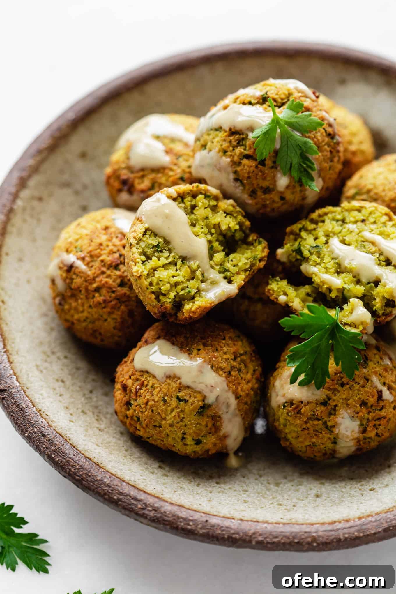 Crispy Air Fryer Falafel Recipe with Tahini Sauce 2 falafel on a ceramic plate drizzled with tahini