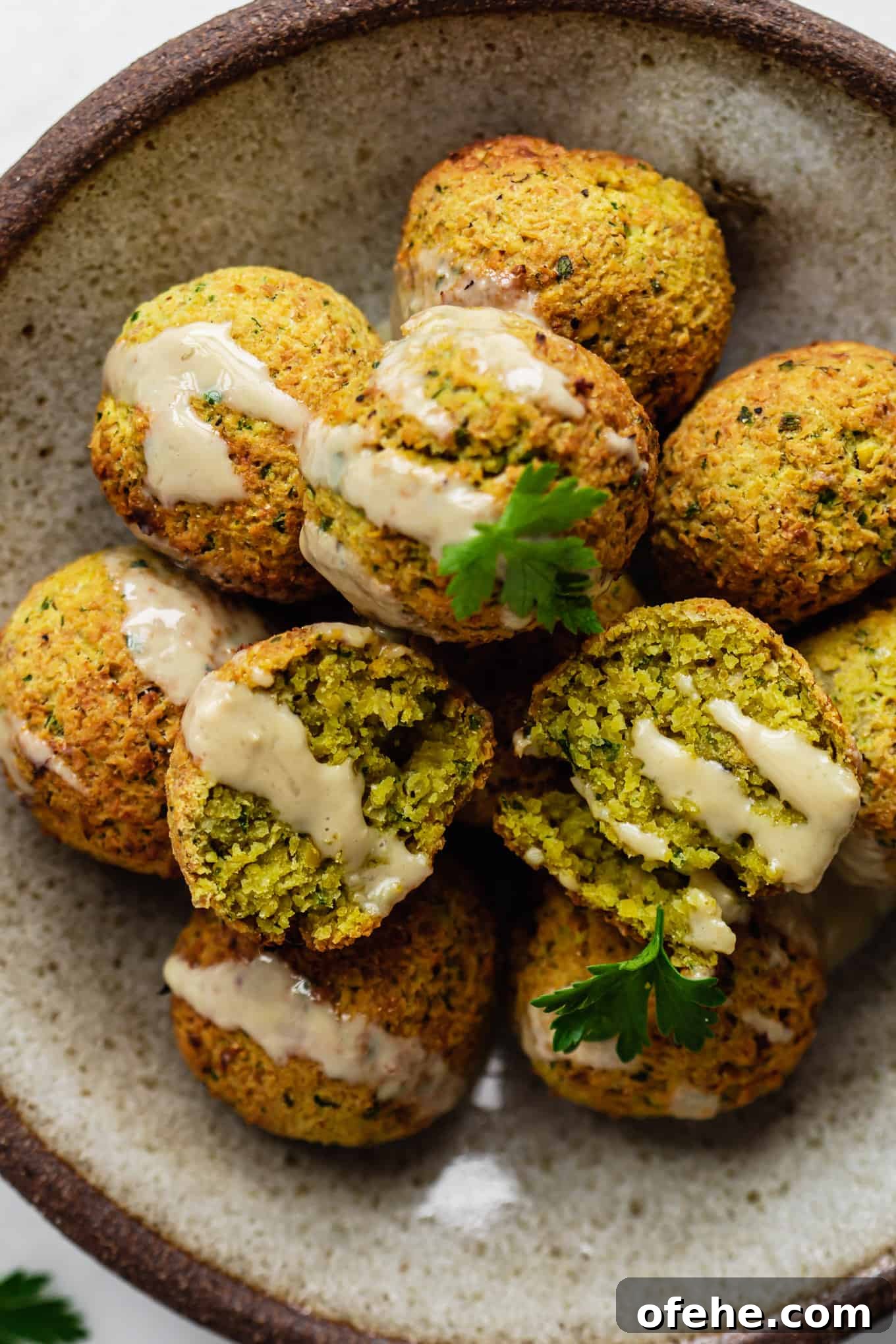 Crispy Air Fryer Falafel Recipe with Tahini Sauce 9 falafel balls on a plate topped with tahini and parsley