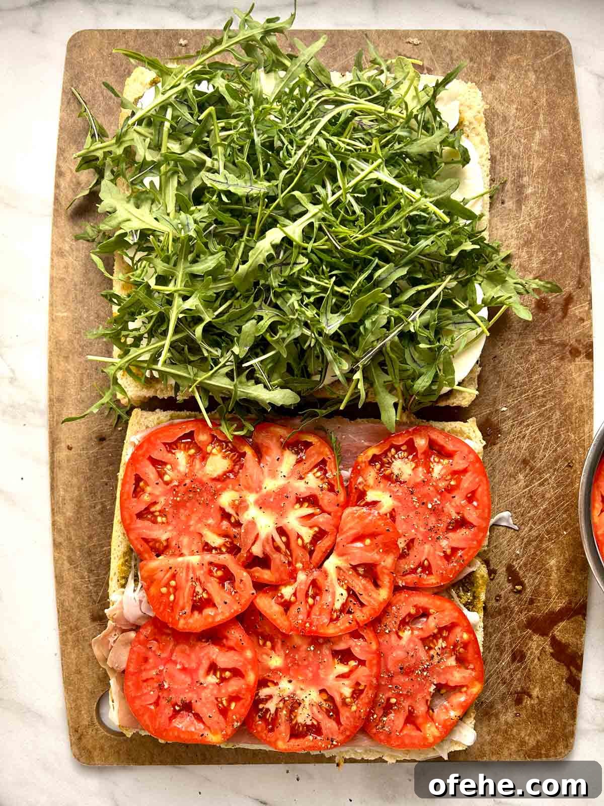 arugula and tomatoes added to focaccia halves.