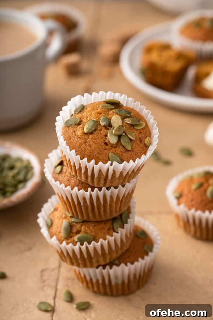 Moist Pumpkin Muffins with Warm Spices Recipe 11 Four pumpkin muffins stacked on a tile counter