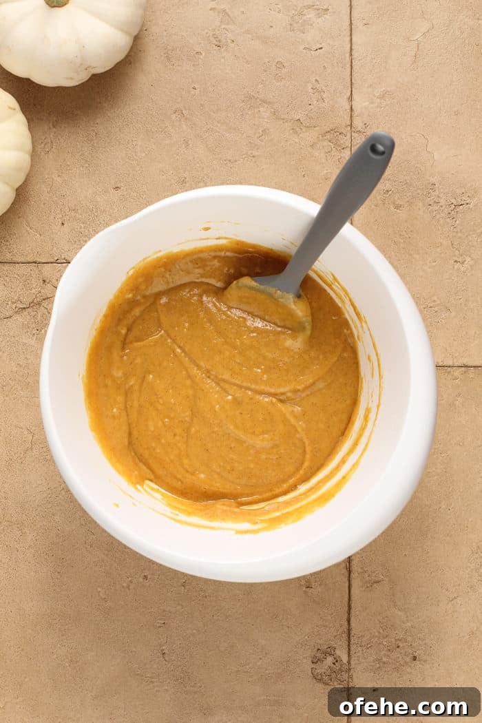 Moist Pumpkin Muffins with Warm Spices Recipe 6 Spatula stirring together pumpkin muffin batter in a white mixing bowl