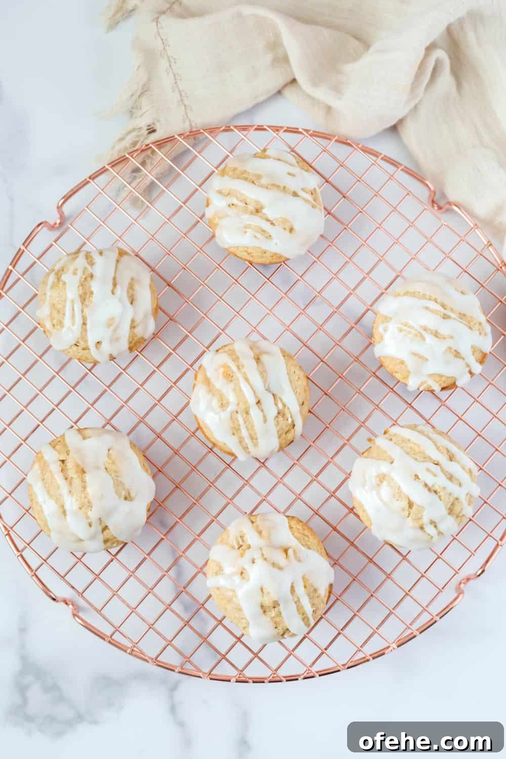 Peach Muffins Made with Bisquick — Quick Summer Treat 3 Overhead view of peach muffins with icing on a wire rack.