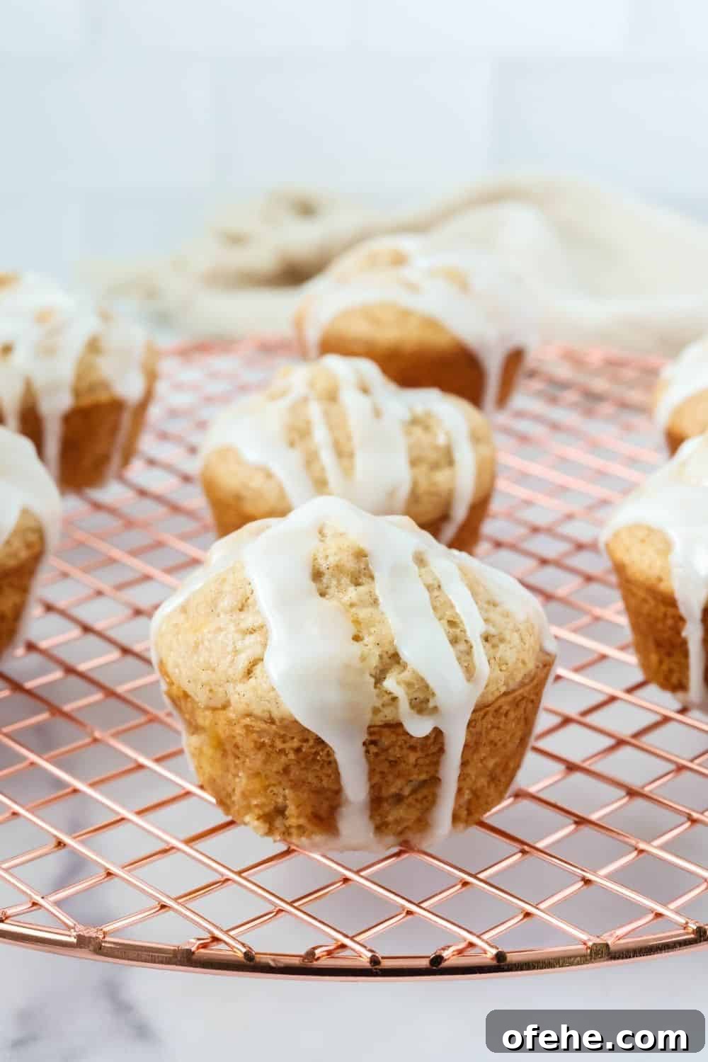 Peach Muffins Made with Bisquick — Quick Summer Treat 5 Several moist peach muffins, topped with icing, on a wire cooling rack.