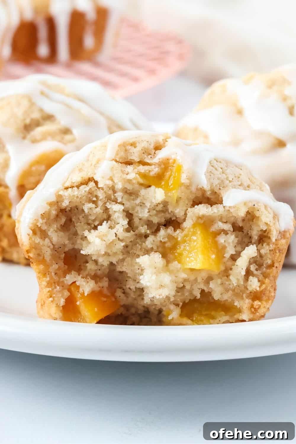 Peach Muffins Made with Bisquick — Quick Summer Treat 10 Close-up view of a fluffy peach muffin that's been torn in half, showingchunks of sweet peaches in the muffin.