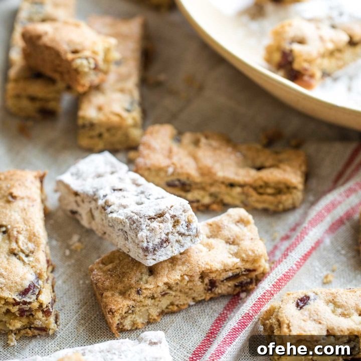 Date bars laying will-nilly on an old-fashioned tan cloth - some have been rolled in powdered sugar and some have not yet.