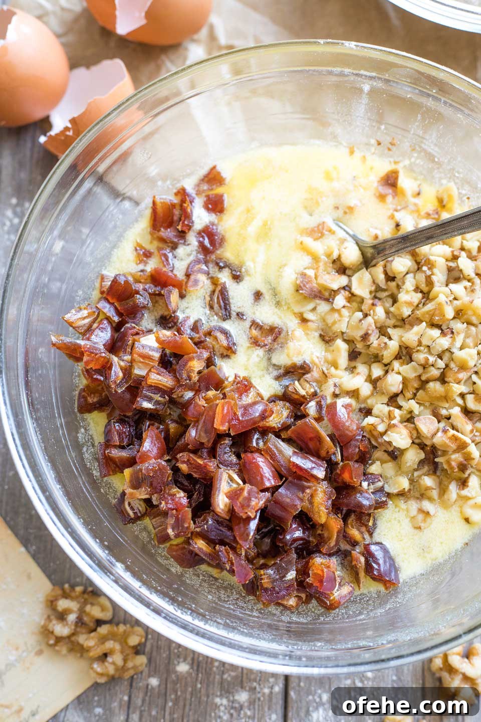 Overhead shot of the wet ingredients, plus dates and nuts, in a glass mixing bowl, ready to be stirred together.