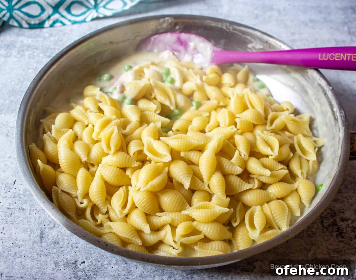 Creamy Ham and Pea Pasta Recipe for Quick Weeknight Dinners 4 Pasta shells in a saucepan on top of a creamy sauce.