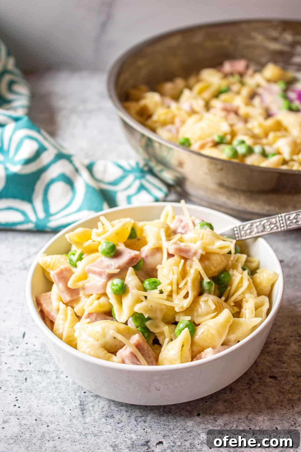 Creamy Ham and Pea Pasta Recipe for Quick Weeknight Dinners 6 A bowl of pasta with a pan of pasta in the background.