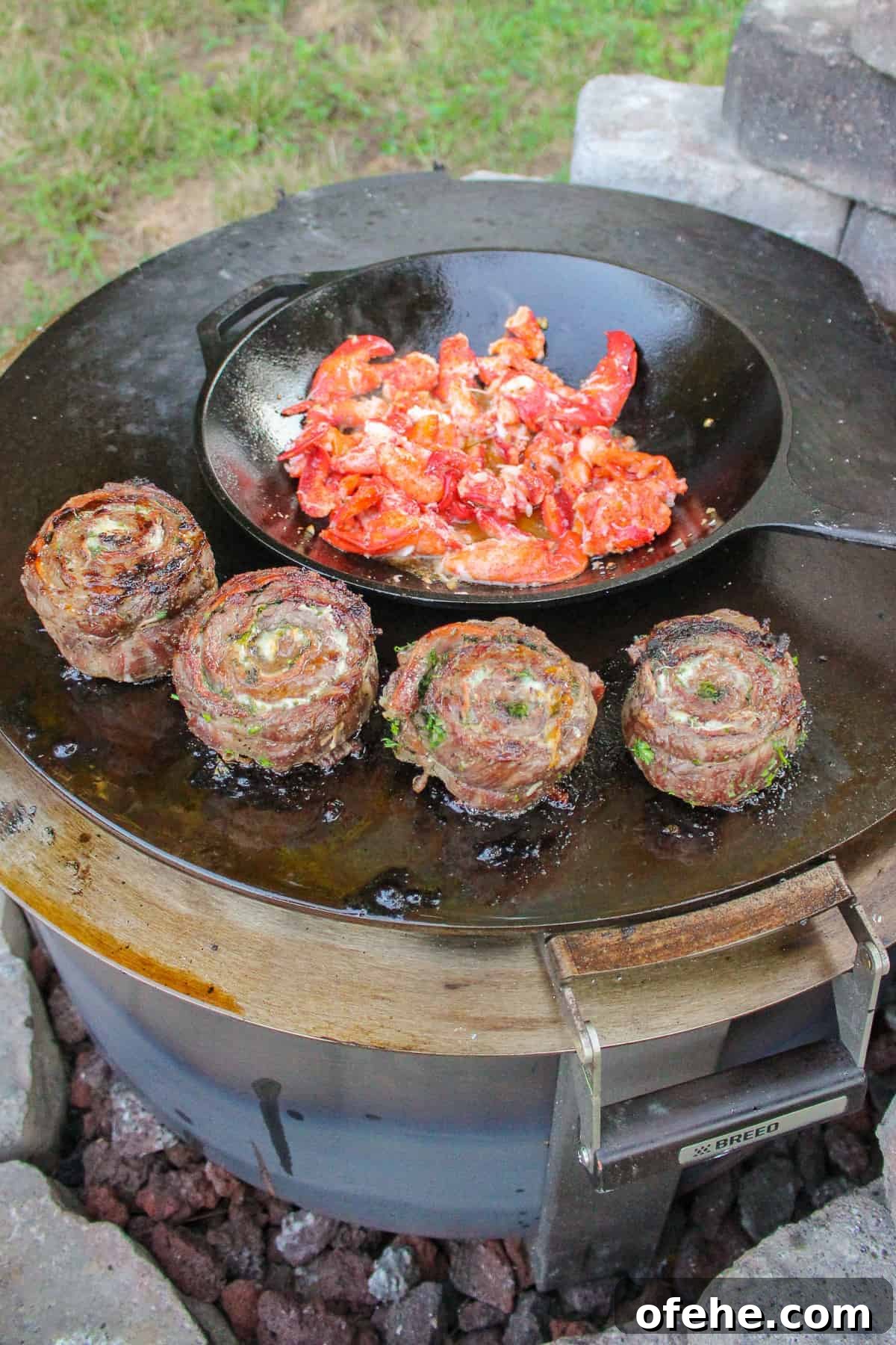 Top Surf and Turf Recipes for Dinner: Steak and Seafood Ideas 4 Cooking some steak pinwheels on the grill and lobster in a cast iron wok.