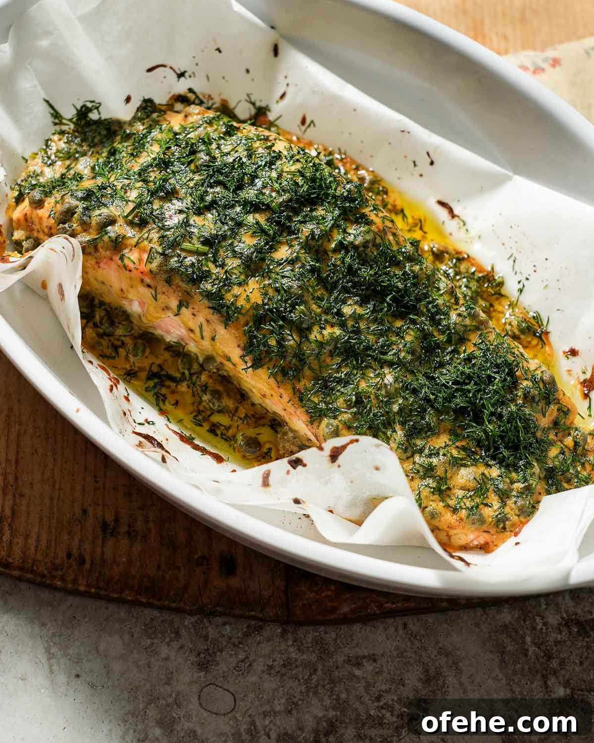 Oven-Baked Dijon Salmon with Fresh Dill and Lemon 2 Dijon mustard dill salmon after being cooked in a baking dish with parchment paper.