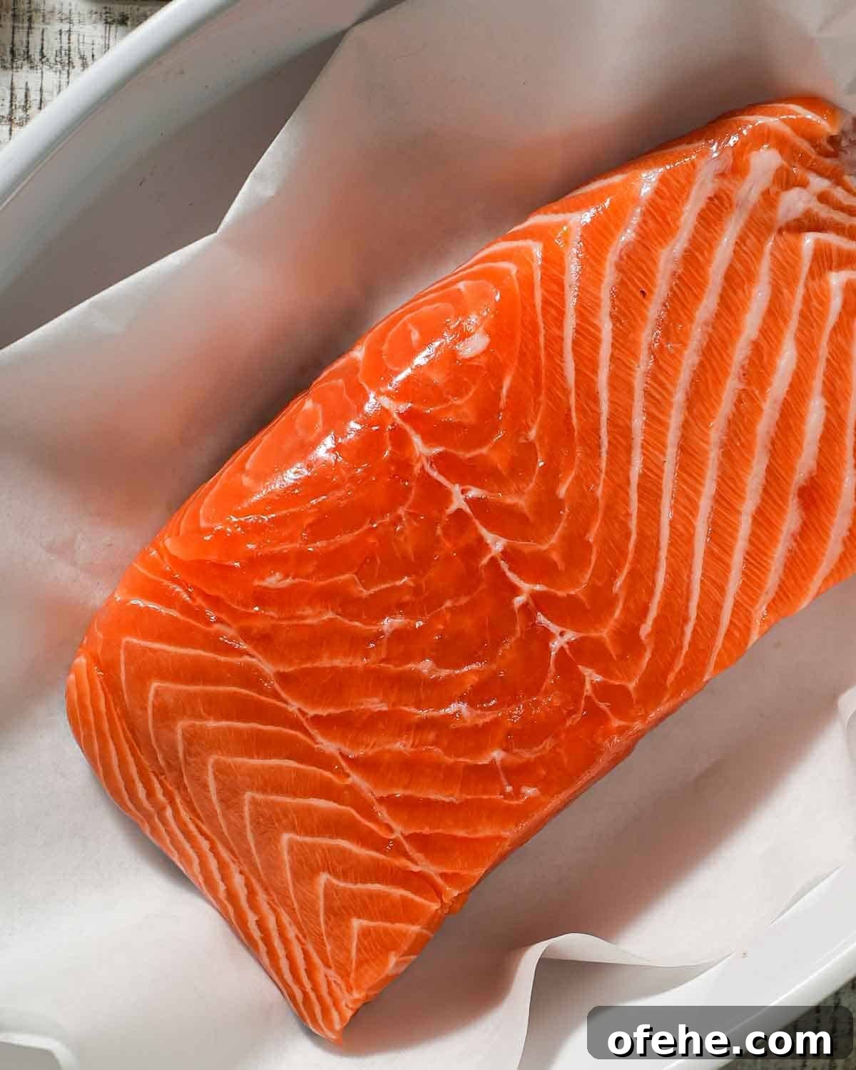 Oven-Baked Dijon Salmon with Fresh Dill and Lemon 4 A salmon fillet in a baking dish lined with parchment paper.