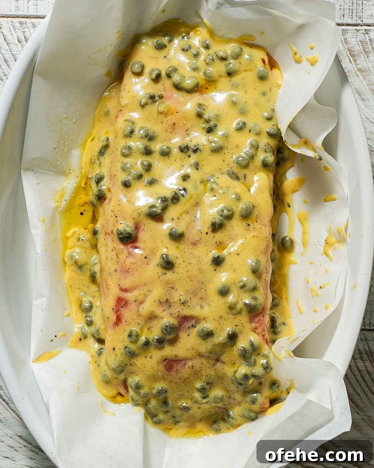 Oven-Baked Dijon Salmon with Fresh Dill and Lemon 5 Dijon mustard marinade over salmon in a baking dish before baking.