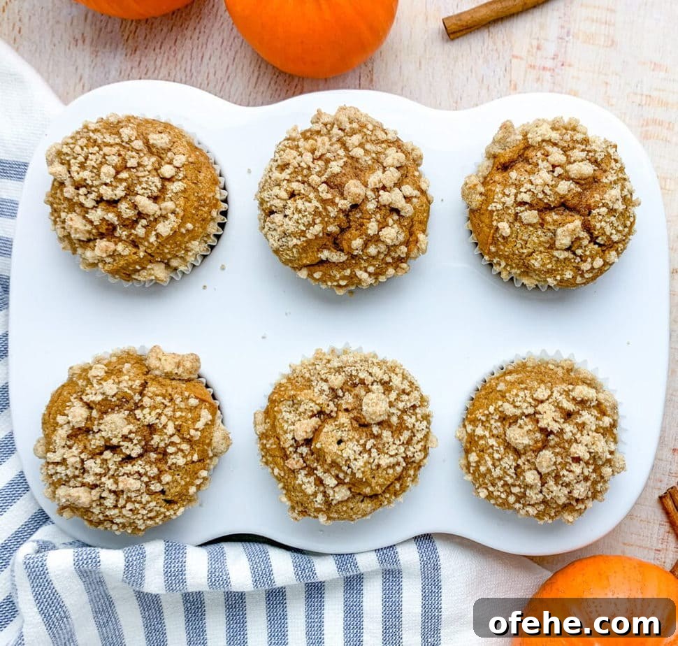Pumpkin Streusel Muffins with Cinnamon Crunch Topping 6 A table topped with muffins in a muffin pan. Pumpkins and cinnamon stick off to the side.