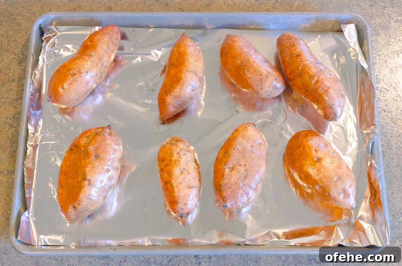 Savory Roasted Sweet Potato Mash with Garlic and Herbs 4 baked sweet potatoes on a foil lined pan ready to be bakes