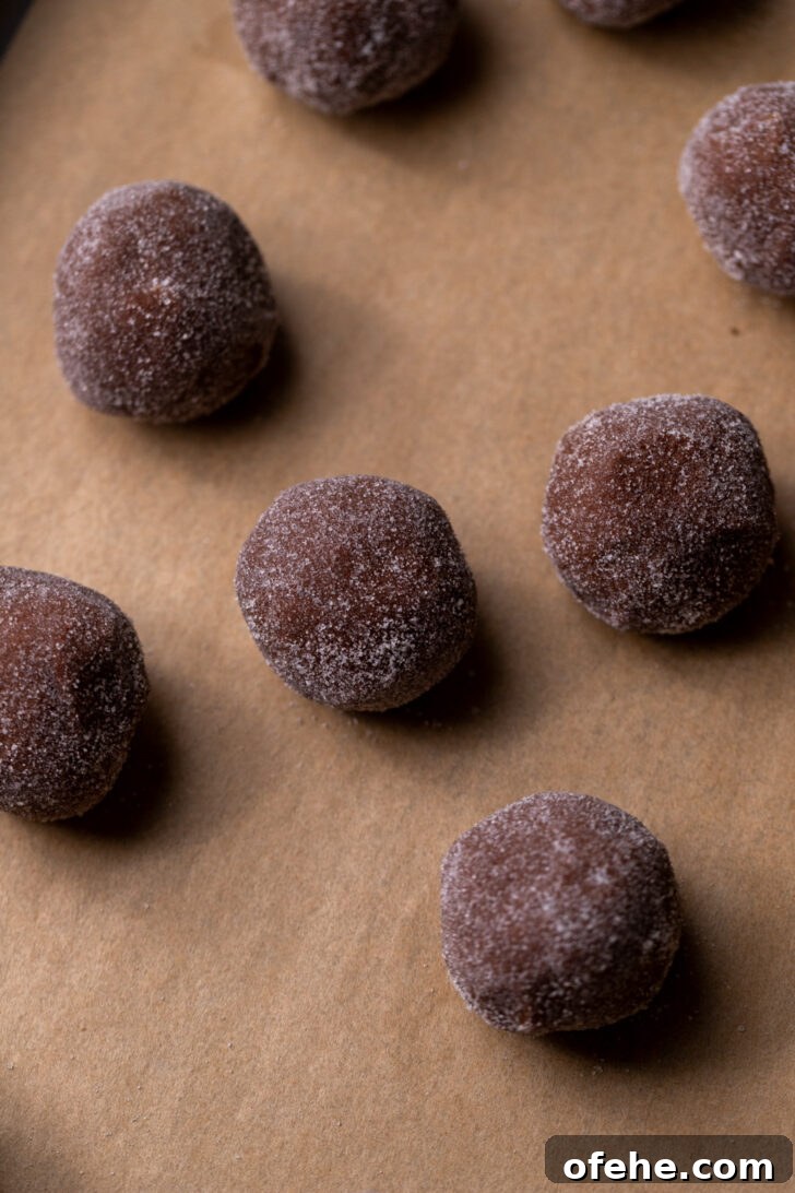 Chocolate Thumbprint Cookies with Gooey Jam Centers 5 Rolled cookie dough balls on a cookie sheet.