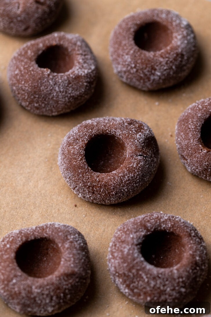 Chocolate Thumbprint Cookies with Gooey Jam Centers 6 Cookie dough balls with a hole in the middle.