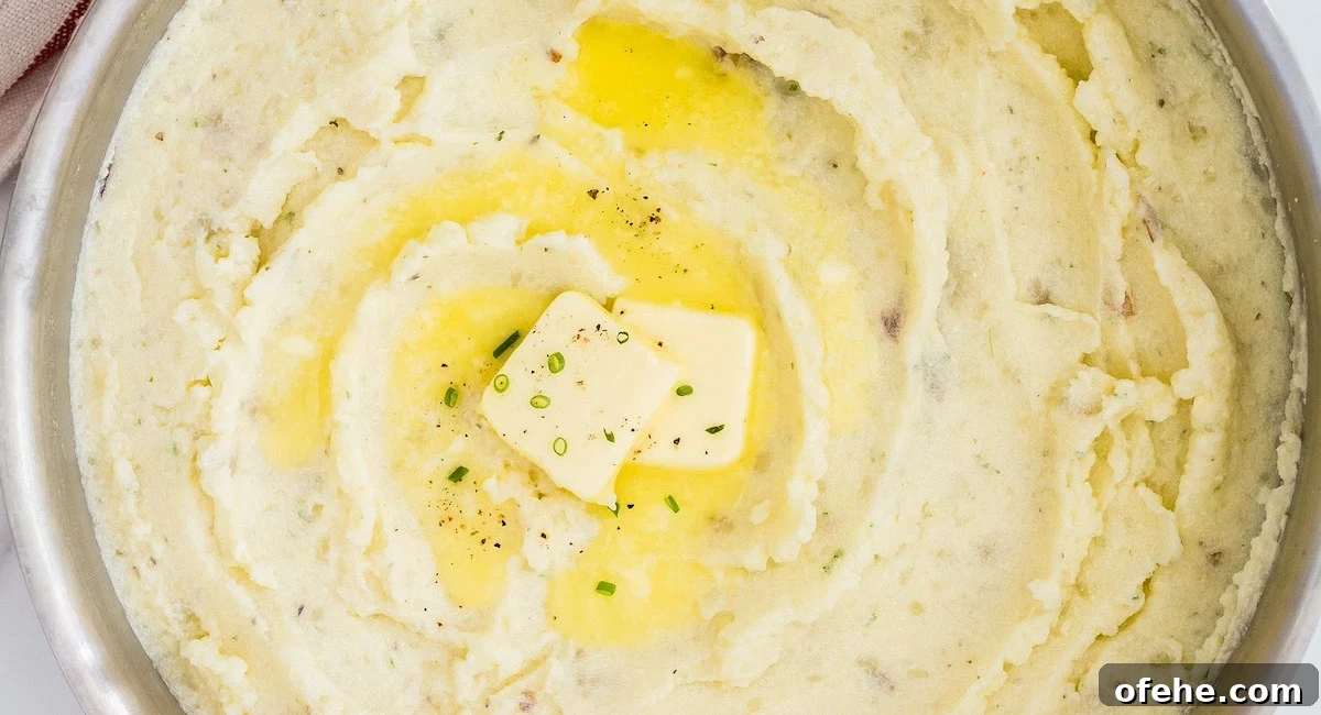 Overhead image of garlic herb mashed potatoes with butter and garnish.